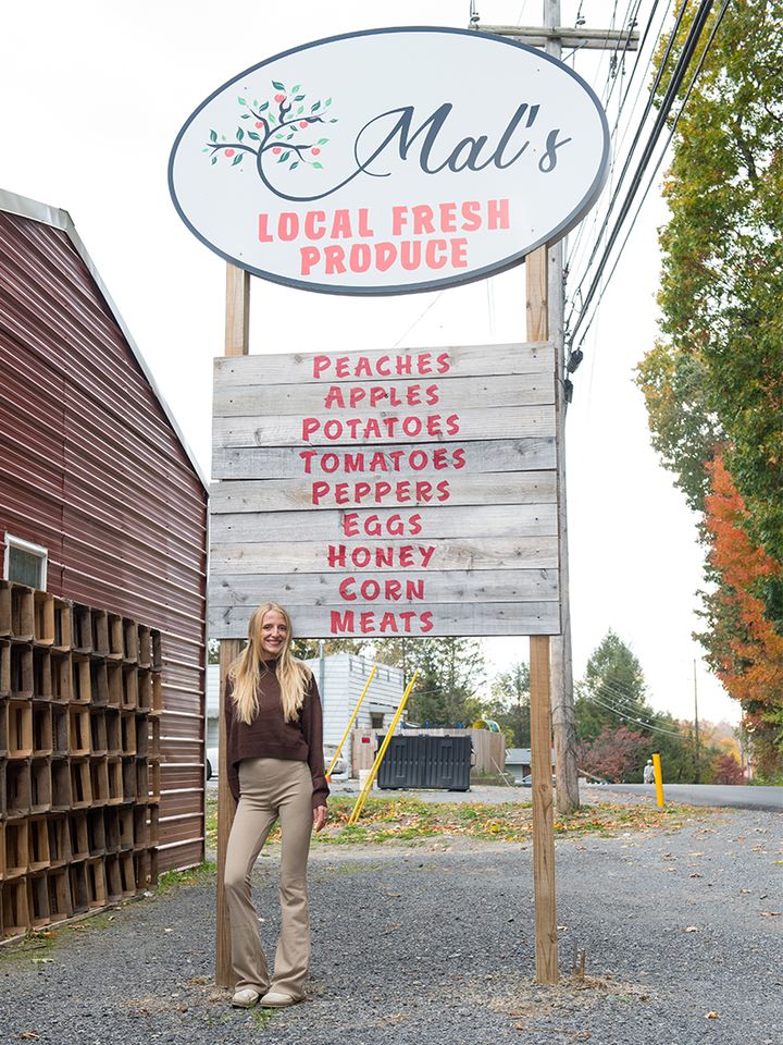 Photo of Mal Moholt standing in front of her store's sign