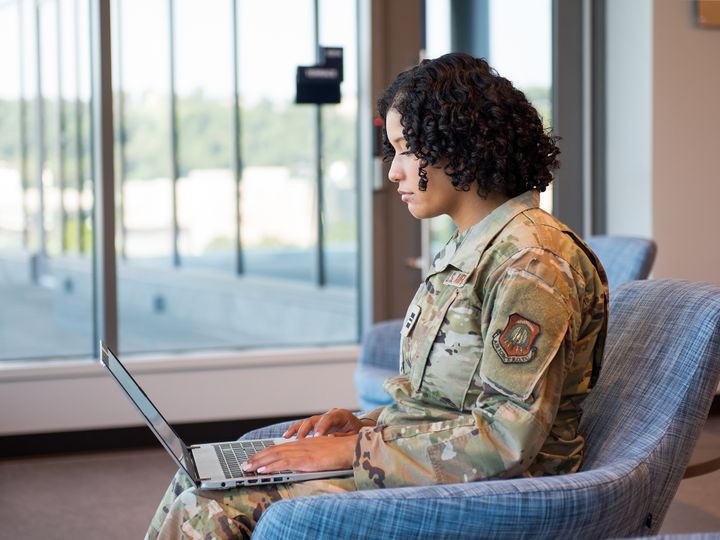 Photo of Jade Porter, in uniform, using her laptop in Reynolds Hall