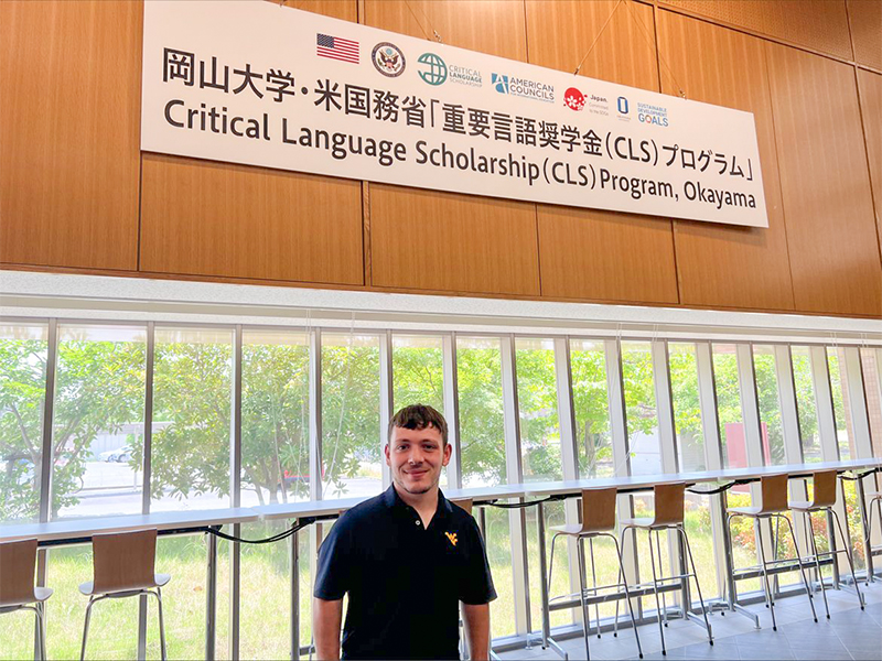 Photo of Matthew Kinzer in front of a welcome sign in Japan