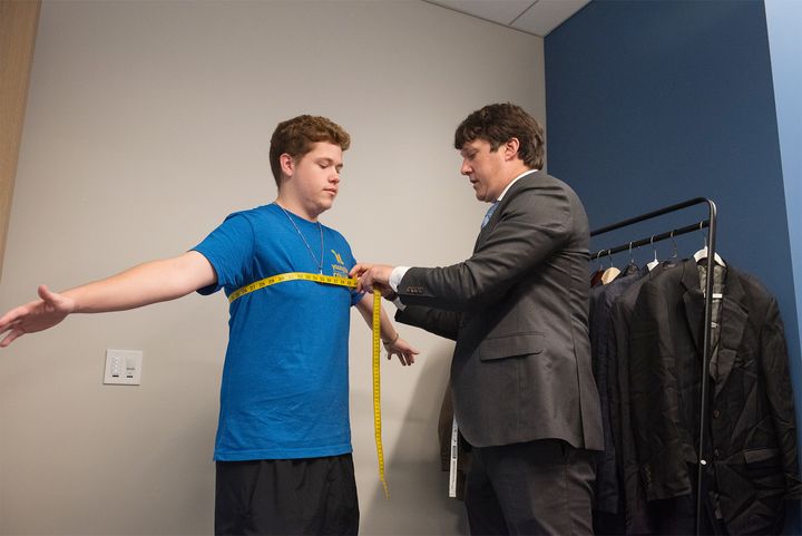 Photo of a professional measuring a student in the Career Closet
